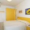 Camera con letto matrimoniale, pareti bianche, decorata con quadri e dettagli gialli.