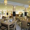 Sala da pranzo con tavoli e sedie di vimini, bottiglia di vino su un tavolo.