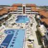 Complesso di piscine con vista aerea, circondato da edifici arancioni.