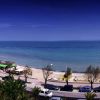 Spiaggia panoramica con strada e auto, mare blu sullo sfondo.