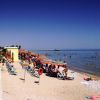 Spiaggia con ombrelloni arancioni, sedie a sdraio e persone che nuotano nel mare.