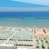 Ombrelloni colorati disposti ordinatamente su una spiaggia sabbiosa vista mare.