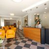 Reception di un hotel con sedie gialle e personale alla scrivania. Piastrelle pavimentali a scacchi.