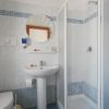 Un bagno con doccia, lavabo, specchio rotondo e piastrelle a mosaico blu e bianche.
