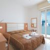 Camera d'albergo con letto matrimoniale, pareti bianche, balcone e vista mare.