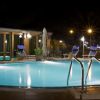 Piscina illuminata di notte con sedie a sdraio.