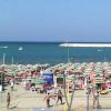 Spiaggia gremita di ombrelloni colorati e mare sullo sfondo.