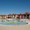 Piscina circolare con sdraio, case colorate sullo sfondo.