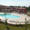 Complesso residenziale con piscina centrale e numerose sedie a sdraio.