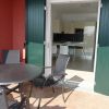 Terrazza con tavolo e sedie nere. Portafinestra con persiane verdi che conduce a una cucina moderna.