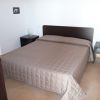 Stanza da letto con letto matrimoniale coperto da trapunta marrone e due comodini con lampade.