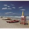 Spiaggia con pedalò, canoa e attrezzature di salvataggio sulla sabbia.