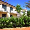 Una casa a due piani con balconi, circondata da un giardino verde e un cielo blu.