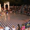 Folla in un anfiteatro all'aperto osserva bambini che giocano.