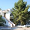 Edificio bianco a due piani con una scala esterna, alberi intorno.