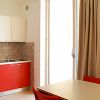 Cucina moderna con mobili rossi, tavolo con sedie rosse, tenda beige.