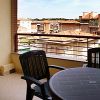 Balcone con tavolo e sedie nere, vista su tetti e edifici circostanti.