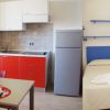 Interno di un appartamento con angolo cottura rosso e area notte con letto matrimoniale.