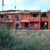 Edificio rosso a due piani con tetto in tegole, circondato da vegetazione e lavanda in primo piano.