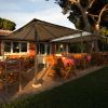 Terrazza esterna di un ristorante con tavoli apparecchiati e sedie in legno.