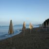 Ombrelloni chiusi su una spiaggia sabbiosa al tramonto.