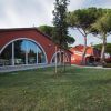 Edificio rosso con grandi finestre ad arco, circondato da alberi.