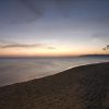Spiaggia deserta al tramonto con cielo colorato e mare calmo.