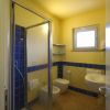 Bagno con doccia moderna, piastrelle blu, lavabo e wc, illuminato da una finestra.
