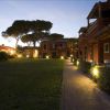 Pathway illuminato al crepuscolo tra edifici rossi e un vasto prato.