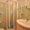 Bagno con doccia e lavabo bianchi.