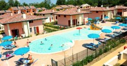Piscina circondata da case, ombrelloni blu.