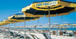 Spiaggia con ombrelloni a strisce gialle e blu e sedie da mare.