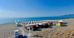 Spiaggia con ombrelloni, cabine e mare calmo sullo sfondo.