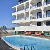Piscina circondata da lettini e edificio bianco a più piani.