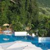 Piscina circondata da ombrelloni e vegetazione verde.