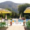 Tavolini e sedie verdi sotto ombrelloni vicino a una piscina.