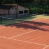 Due persone giocano a tennis su un campo in terra battuta.