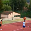 Persone giocano a tennis con una palla arancione su un campo all'aperto.