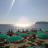 Spiaggia con ombrelloni e sole riflesso sul mare.