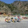 Persone su lettini su una spiaggia con montagne.