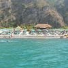 Spiaggia affollata, ombrelloni colorati e ristorante sullo sfondo.