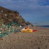 Spiaggia con lettini, ombrelloni e pedalò giallo.