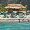 Persone in acqua e ombrelloni su una spiaggia affollata.