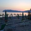 Spiaggia all'alba con lettini e ombrelloni chiusi.