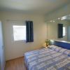 Letto matrimoniale con copriletto blu, specchio, finestra e armadio.