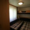 Cameretta con letto a castello e due letti singoli, tenda bianca.