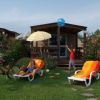 Due bambini in un giardino con lettini e bici, davanti a bungalow.