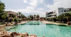 Ampia piscina all'aperto, circondata da vegetazione e edifici.