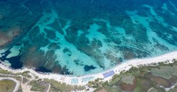 Vista aerea di una spiaggia con mare turchese e tratti rocciosi.