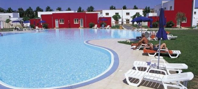 Piscina curvilinea con lettini e ombrelloni blu.